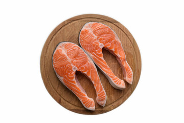 There are two steaks of red fish on a round wooden cutting board. On white clipping background
