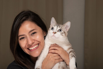 Happy woman and her withe cat with stripes looking at the camera posing for a picture