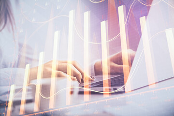 Double exposure of woman hands working on computer and forex graph hologram drawing. Financial...