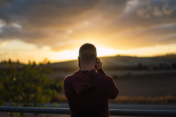 Fototapeta premium Chico joven con mascarilla negra con el atardecer de fondo