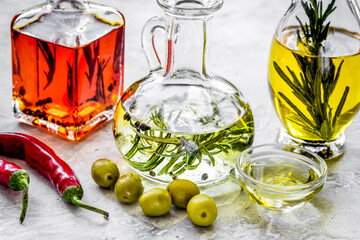 Bottles with pumpkin, chili and olive oils and herbs on stone background