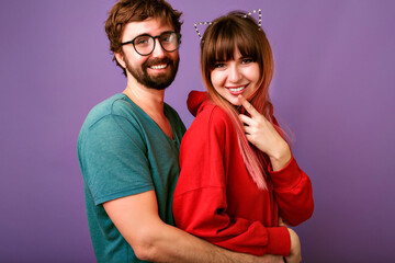 Studio portrait of young hipster pretty family couple hugs and looking on camera, wearing trendy casual outfits, boyfriends and girlfriends, relation goals, violet background.