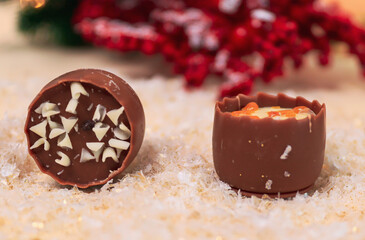 belgian chocolate and christmas decor
Two Belgian chocolates and Christmas decor on a light background, close-up side view.