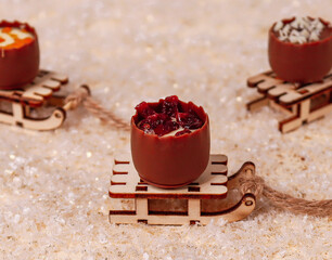 Belgian chocolate on a sled
Belgian milk chocolate in the form of a barrel with dry fruits on top lies on a sled in the snow, a very close-up side view.