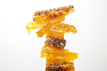 Drops of fresh honey dripping from a pyramid of wax honey. vitamin nutrition and bee product.