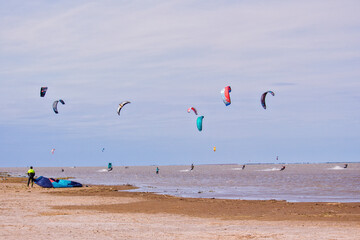 group of kitesurfers practicing a cloudy day - man on the beach