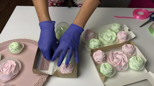 A woman lays out pink and light green zephyr in gift cardboard boxes
