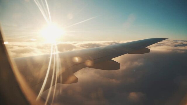 Airplane flight. Wing of an airplane flying above the clouds with sunset sky.