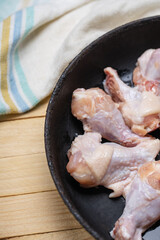 fresh chicken wings at frying pan on a wooden desk. cooking hen wing