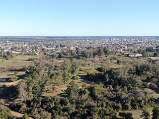 Foto aérea panorámica de un parque, con una ciudad de edificios bajos en el fondo. 