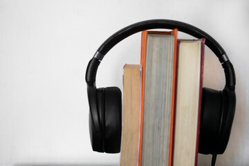 Headphones put on books in white background. Concept  Audiobook.