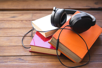 Headphones on a set of books on a wooden table. Concept Audiobook.