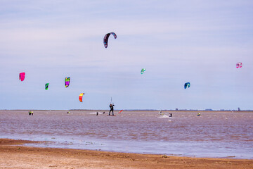 men practicing kitesurfing in a lagoon - in the air