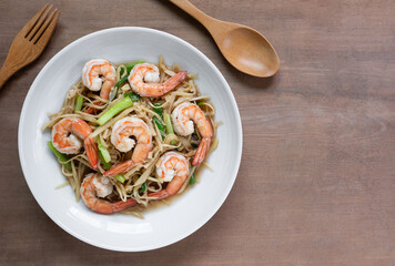 top view of stir fried shrimps iwith ginger in a ceramic dish on wooden table. homemade style healthy food concept.
