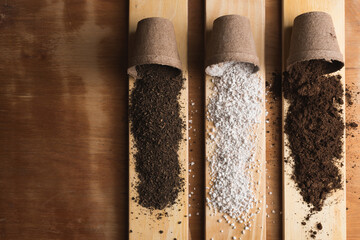Peat, perlite and worm humus for soil mix on pine wood boards and a raw wooden background with space for text.
