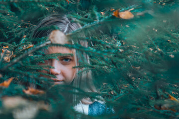 a girl wanders through the woods, peeps out from under the Christmas tree, in search of a way. The girl's gaze through the foliage in the woods.