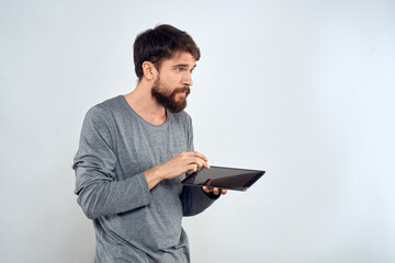 A bearded man with a tablet in his hands a gray jacket technology internet light background