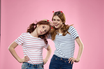 Cheerful mom and daughter lifestyle joy striped shirts family pink background