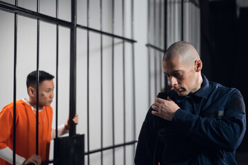 A stern, bald prison warden makes the rounds of the cells and transmits information over the radio...