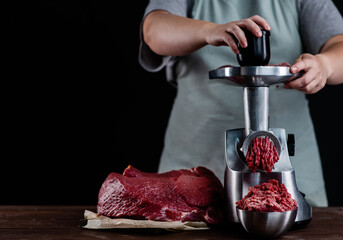 The cook puts the   meat in a meat grinder, minced  appears from the meat grinder. The process of...