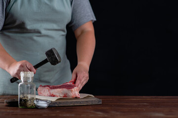 In front of the cook lies a meat tenderloin and the cook beats the entrecote with a special hammer