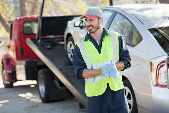 Smiling male roadside assistance worker towing car3/28/2020