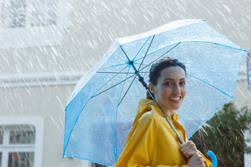 Portrait smiling woman with umbrella in rain © Martin Barraud/Caia Image