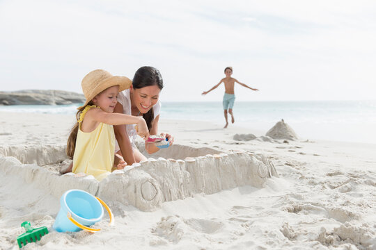 Mother and daughter building sandcastle on beach