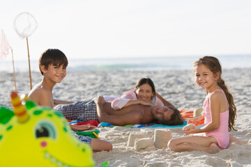 Obraz premium Portrait happy family relaxing and making sandcastle on sunny beach