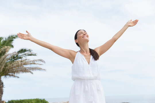 Portrait carefree woman with arms outstretched on ocean patio