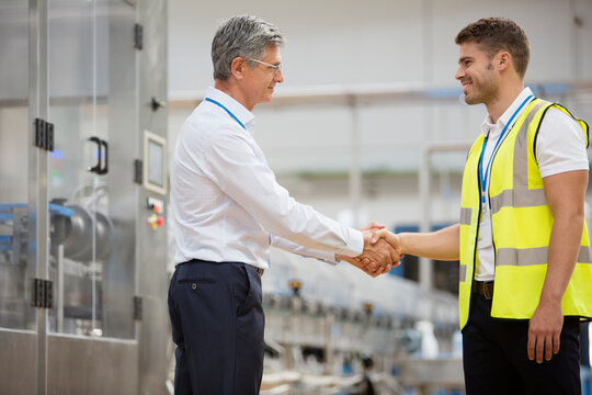 Male manager shaking hands with worker in factory