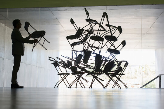 Businessman stacking chairs in office