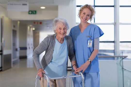 Portrait smiling female nurse helping senior woman with walker in hospital