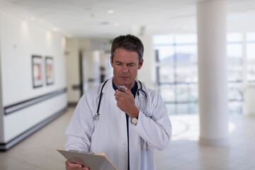 Fototapeta premium Male doctor dictating notes into tape recorder in hospital