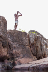 Fototapeta premium Young man in swim trunks on rocks