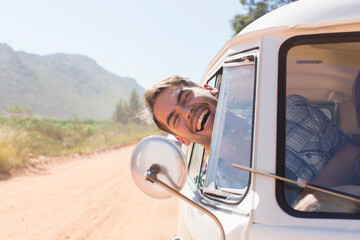 Portrait happy young man leaning out sunny van window