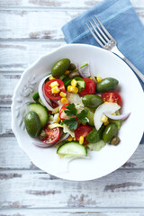 Healthy Salad with Green Olives, Baby Spinach, Cucumber, Cherry Tomatoes and Capers. Bright wooden background. Top view. Close up.	