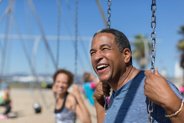 Obraz premium Happy senior man on swing set on sunny beach