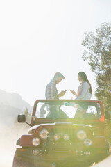 Young couple using smart phones in sunny jeep © Martin Barraud/Caia Image