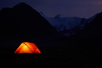 Fototapeta na wymiar Tent Glowing red under in Belukha Mountain, Altai, a night sky full of stars.