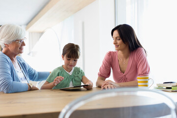 Fototapeta premium Multi-generation family using digital tablet at dining table