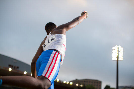 Male track and field athlete throwing shot put