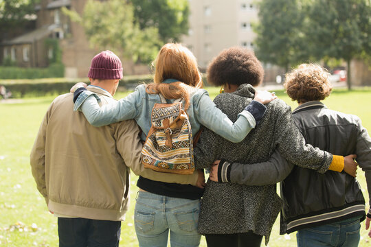 Young friends hugging and walking in sunny park