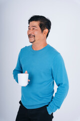 Senior man in blue long sleeve shirt with white coffee cup.