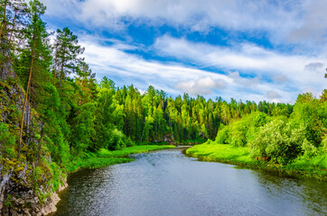 The river flows among mountains covered with forest.