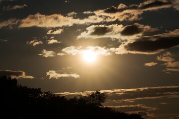 This image shows a dramatic sun setting amongst a cloudy sky.