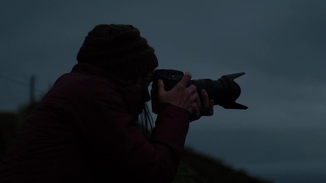 Photographer woman taking pictures in dark moody cinematic fog