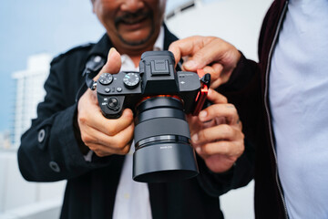 Two senior men holding mirrorless camera.