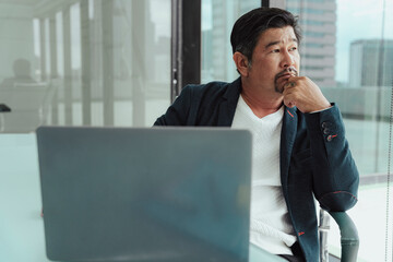 Serious asian business man working on laptop in meeting room.