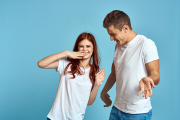 Fototapeta premium enamored man and woman in jeans and a T-shirt on a blue background hug each other and have fun